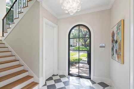 Foyer with an inviting chandelier, tile patterned flooring, and ornamental molding