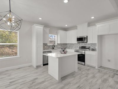 Kitchen featuring stainless steel appliances, sink, pendant lighting, white cabinets, and a center island