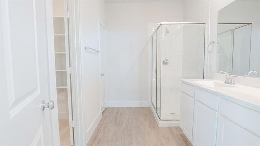 Bathroom featuring hardwood / wood-style floors, vanity, and a shower with shower door