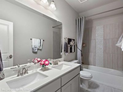 Full bathroom featuring tile patterned flooring, double vanity, shower / bath combination with curtain, and toilet