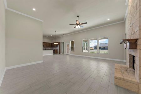 Unfurnished living room featuring ceiling fan, crown molding, sink, light hardwood / wood-style flooring, and a fireplace