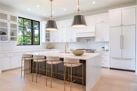 Kitchen featuring paneled fridge, a breakfast bar, a center island with sink, and white cabinets