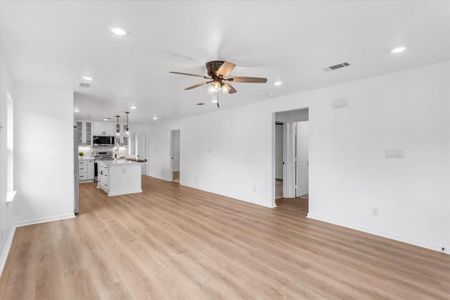 Unfurnished living room featuring ceiling fan and light wood flooring