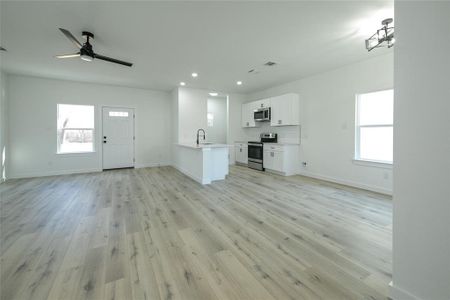 Unfurnished living room with ceiling fan, a healthy amount of sunlight, light hardwood / wood-style floors, and sink