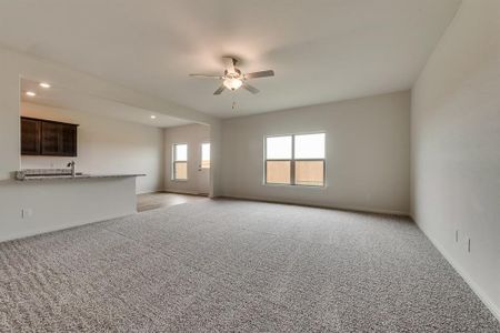 Unfurnished living room with sink, light colored carpet, and ceiling fan