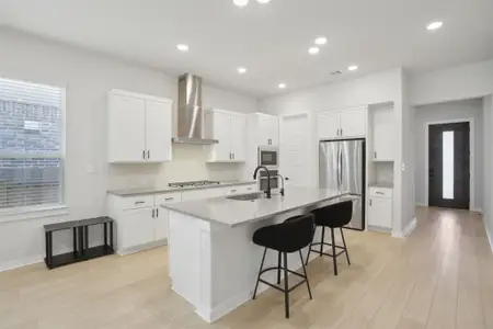 Kitchen featuring stainless steel appliances, a kitchen bar, visible vents, a sink, and wall chimney exhaust hood