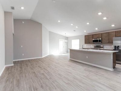 Enjoy an open living area with volume ceilings and low-maintenance vinyl plank flooring - New home for sale in Eagle Lake, FL