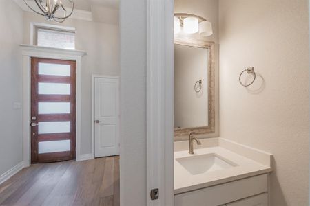 Bathroom with vanity, wood-type flooring, crown molding, and an inviting chandelier