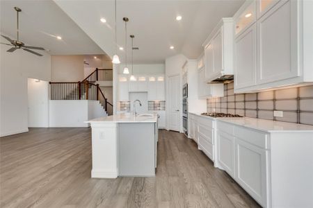 Kitchen featuring light hardwood / wood-style flooring, white cabinets, and a kitchen island with sink