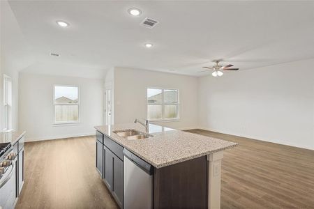 Kitchen with a center island with sink, ceiling fan, dark hardwood / wood-style floors, sink, and stainless steel appliances