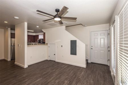 Living room with ceiling fan,wood-style flooring, and storage under staircase