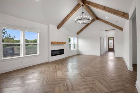 Unfurnished living room with parquet flooring, a chandelier, and lofted ceiling with beams