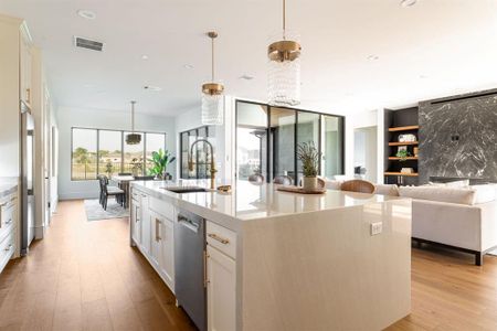 Kitchen with light hardwood / wood-style floors, sink, a center island with sink, and white cabinetry