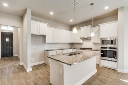 Kitchen featuring light stone counters, appliances with stainless steel finishes, sink, and white cabinets