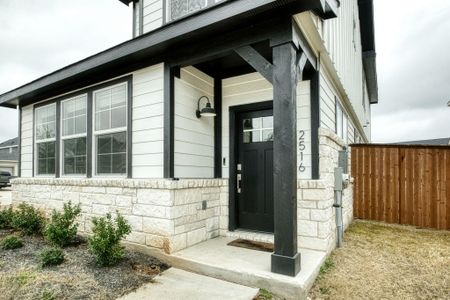 Entrance to property featuring stone siding and fence