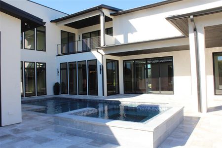 Rear view of house featuring a pool with hot tub, a patio area, and a balcony