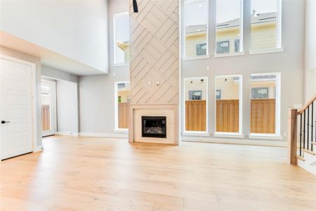 Unfurnished living room featuring a high ceiling and light wood-type flooring