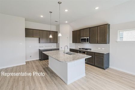 Kitchen featuring sink, light wood-type flooring, decorative backsplash, and stainless steel appliances