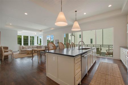 Kitchen featuring a center island with sink, dark hardwood flooring, a tray ceiling