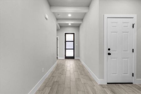 Hall featuring light wood-style floors, beam ceiling, and baseboards