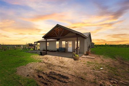 Back of house at dusk featuring a yard, metal roof, and a patio area