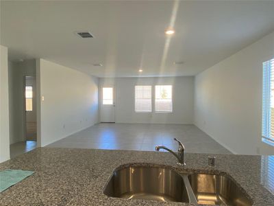 Kitchen with visible vents, open floor plan, tile patterned flooring, a sink, and dark stone counters