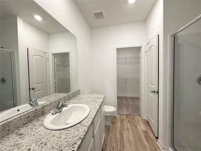 Primary bathroom includes granite counters, designer white cabinetry and luxury vinyl plank flooring.