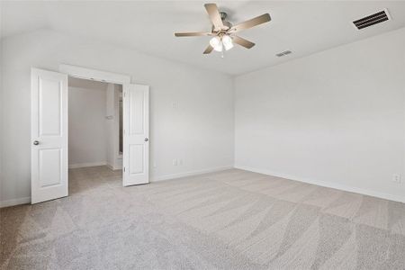 Spare room featuring vaulted ceiling, ceiling fan, and light colored carpet