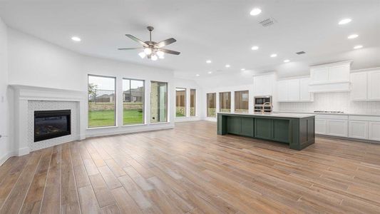 Kitchen with a fireplace, white cabinetry, light hardwood / wood-style flooring, and an island with sink