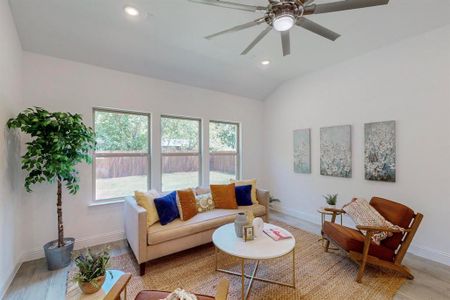 Living room with ceiling fan, vaulted ceiling, and light hardwood / wood-style floors