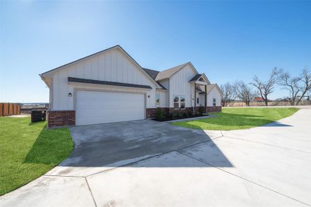 View of front of home with cooling unit, a garage, and a front yard