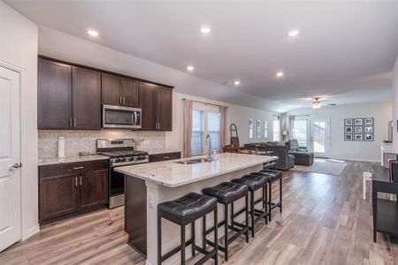 Kitchen featuring appliances with stainless steel finishes, open floor plan, a breakfast bar area, a kitchen island with sink, and a sink