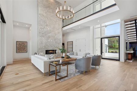 Living room with a towering ceiling, light wood-type flooring, and a premium fireplace