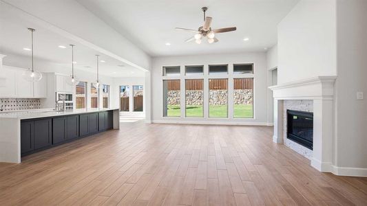 Unfurnished living room with a wealth of natural light, light hardwood / wood-style flooring, and a stone fireplace