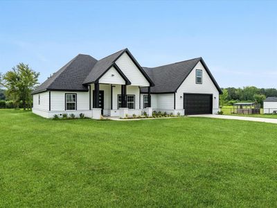 Modern farmhouse featuring a front lawn and a garage