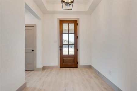 Entryway featuring a tray ceiling, a chandelier, and light hardwood / wood-style flooring