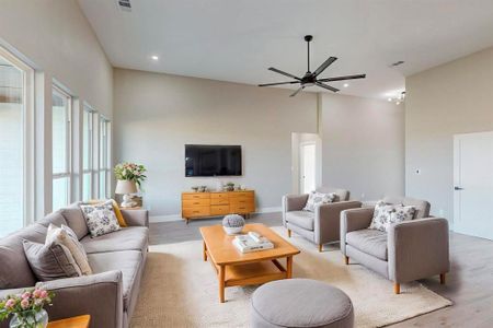 Living room with a towering ceiling, light hardwood / wood-style flooring, and ceiling fan