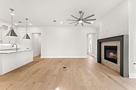 Unfurnished living room featuring a tile fireplace, ceiling fan, vaulted ceiling, and light wood-type flooring