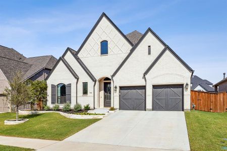 French country style house featuring a garage and a front lawn