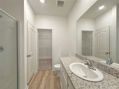 Primary bathroom includes granite counters, designer white cabinetry and luxury vinyl plank flooring.