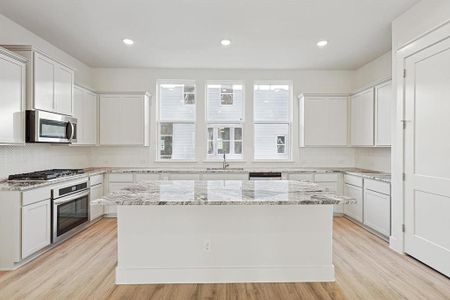 Kitchen featuring backsplash, a center island, light wood-style flooring, stainless steel appliances, and a sink