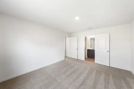 Bedroom featuring light colored carpet and ensuite bath