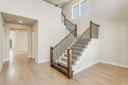 Stairway featuring a towering ceiling and wood-type flooring