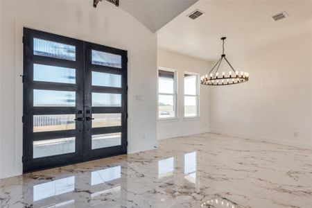 Foyer with french doors, a chandelier, and vaulted ceiling