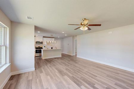 Unfurnished living room featuring ceiling fan and light hardwood / wood-style floors