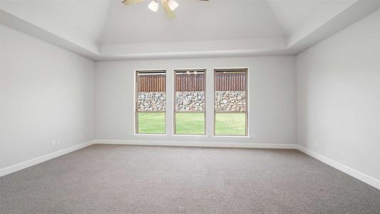 Carpeted spare room featuring ceiling fan and vaulted ceiling