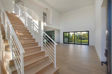 Staircase with wood-type flooring and a towering ceiling