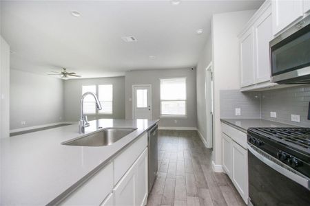 Kitchen featuring sink, backsplash, white cabinetry, appliances with stainless steel finishes