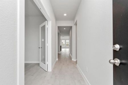 The grand entrance beckons with high ceilings, adorned with elegant wood-look tile flooring and oversized baseboards, and recessed lighting.  Follow path of natural light from expansive windows ahead. Sample photo of completed home with similar floor plan. As-built interior colors and selections may vary.