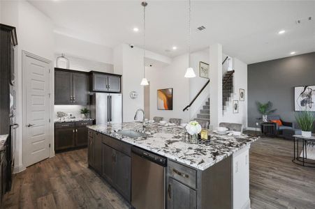 Kitchen with appliances with stainless steel finishes, dark hardwood / wood-style flooring, a kitchen island with sink, sink, and tasteful backsplash